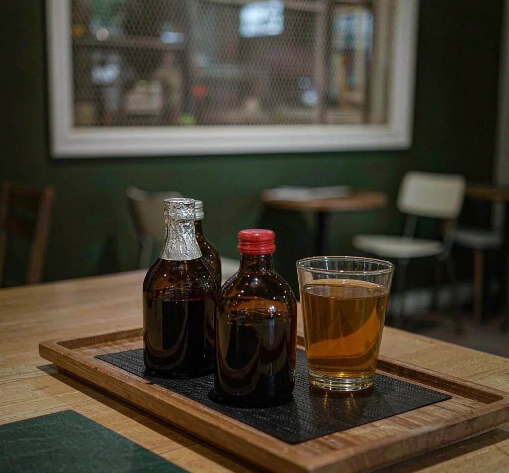 Amber stout glass bottles filled with kombucha on a cafe wooden board