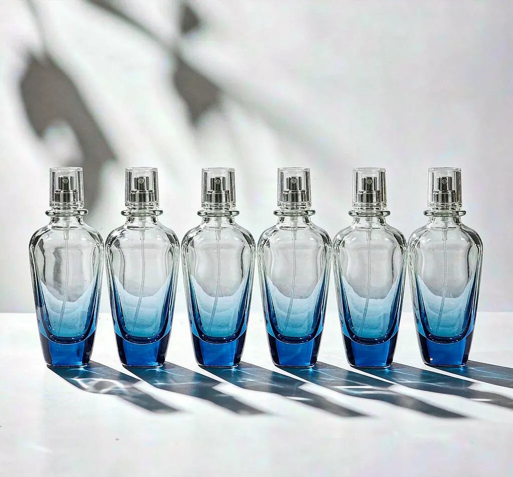 Gradient ombre glass perfume bottles fading from blue to clear