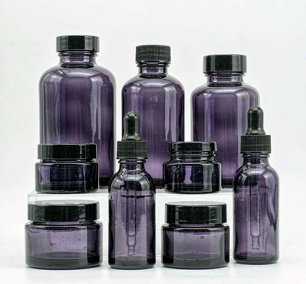 Deep violet glass dropper bottles and jars with black caps in graduated sizes