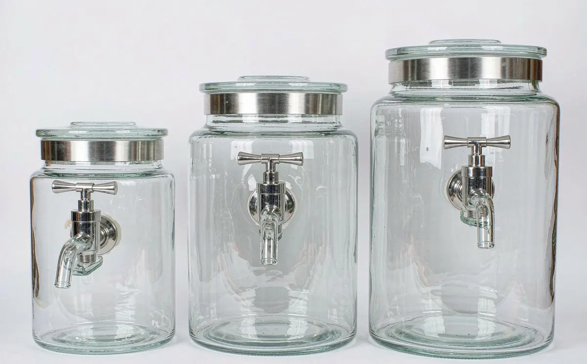 Three glass beverage dispensers with stainless steel spigots and lids