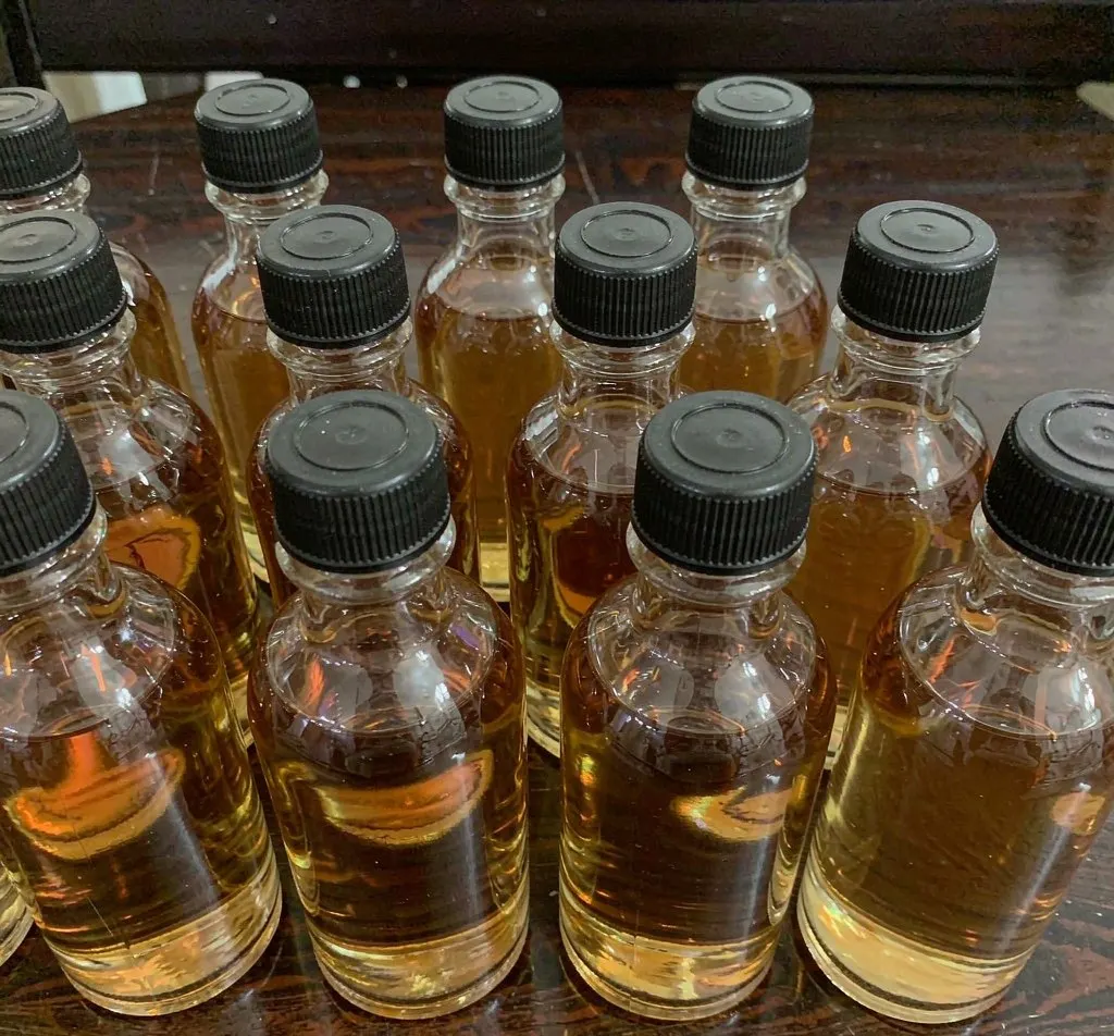 Clear glass woozy bitters bottles with black caps filled with amber liquid