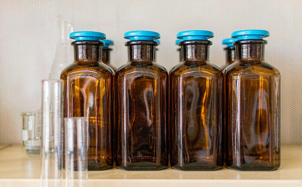 Amber glass reagent bottles with blue caps on a laboratory shelf