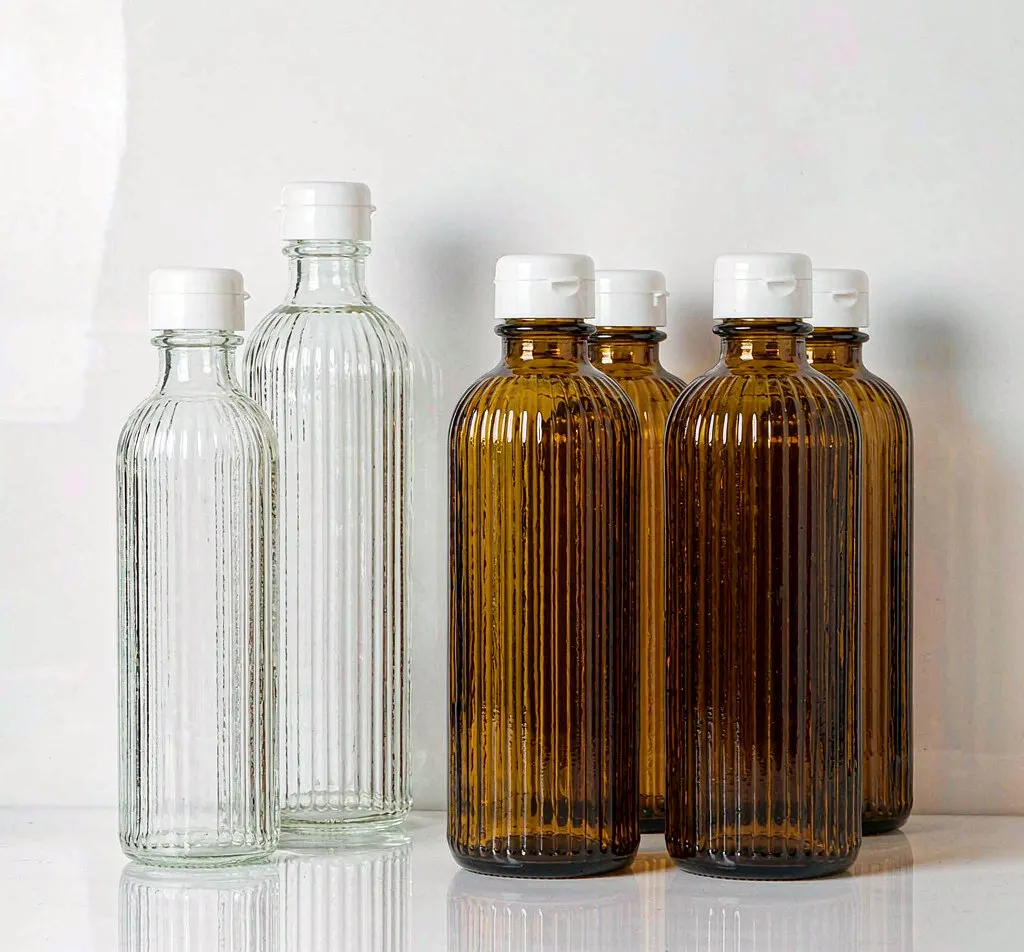 Tall slender clear and amber glass sake bottles with white caps