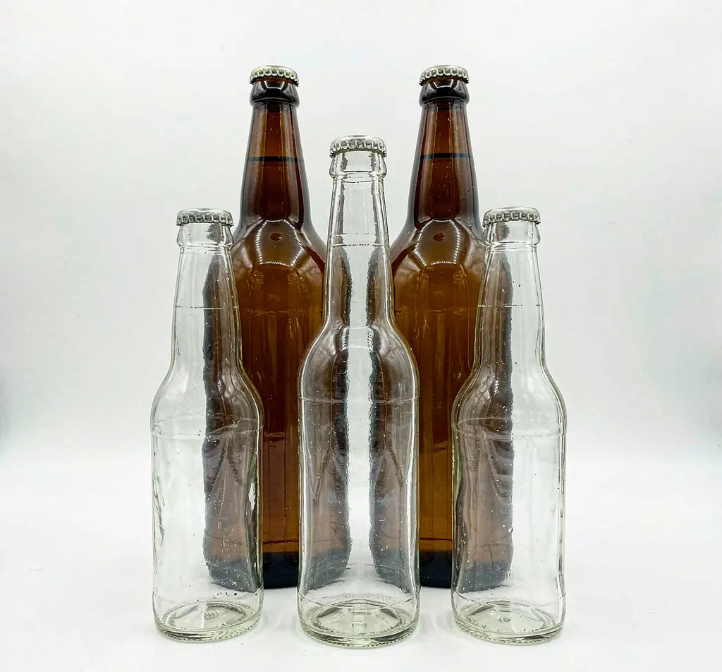 Clear flint and amber glass cider bottles with crown caps in three sizes