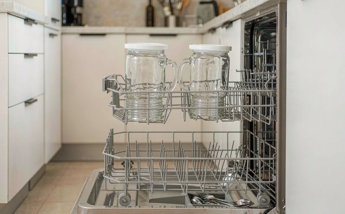 Glass jars sitting on the top rack of a dishwasher