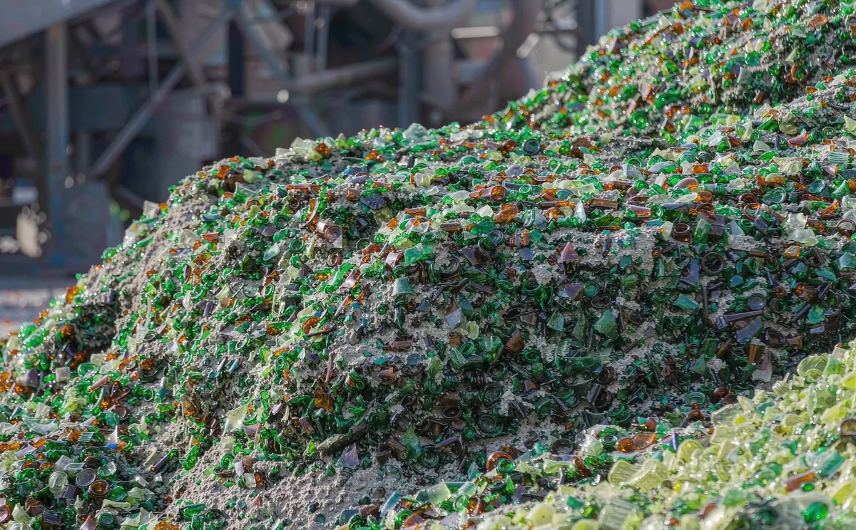 Mixed-color crushed glass cullet piled at a recycling facility, ready for remelting